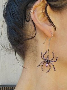 a close up of a person wearing some kind of earring with a spider on it