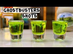 three shot glasses filled with green liquid sitting on top of a counter