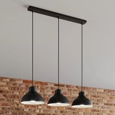 three pendant lights hanging from the ceiling in front of a brick wall with exposed lighting