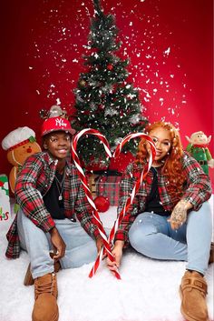 two people sitting next to each other in front of a christmas tree with candy canes