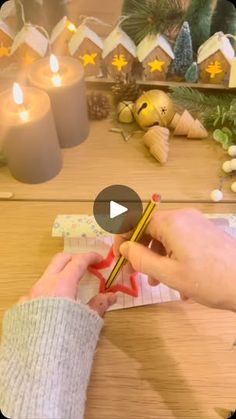 a person holding a pair of scissors in front of christmas decorations and candles on a table