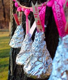 foil wrapped hot dogs hanging from a tree with pink ribbon and tags attached to them