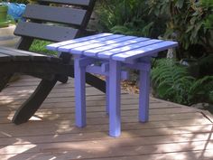 a purple and grey bench sitting on top of a wooden deck next to a green plant