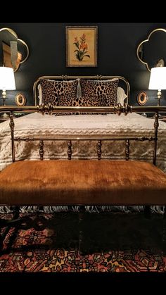 a leopard print bed with two lamps on either side and a bench in the middle