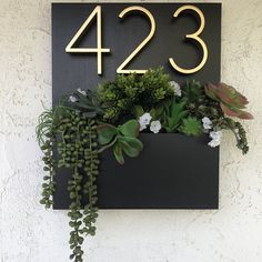 a house number sign with plants growing in it