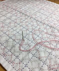 a close up of a piece of cloth on a table with some scissors and thread