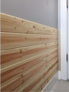 a wall made out of wooden planks next to a white door and gray walls