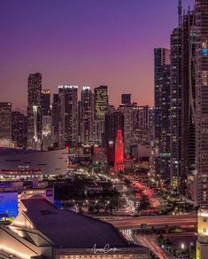 the city skyline is lit up at night with lights on and skyscrapers in the background