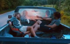 two people sitting in the back of a pick up truck