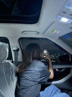 a woman sitting in the back seat of a car while looking at her cell phone