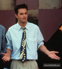 two men standing next to each other with their hands out and one man wearing a blue shirt and tie