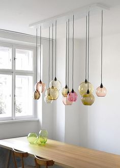 a dining room table with several hanging lights above it