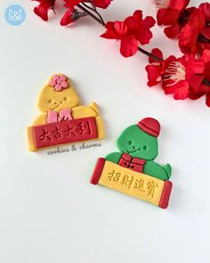 two cookies decorated like teddy bears with chinese writing on them and flowers in the background