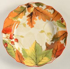 an orange and yellow plate with autumn leaves on the rim is sitting on a white surface