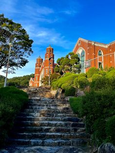 an old building with stairs leading up to the top and below it is surrounded by greenery