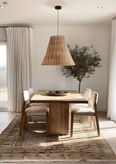 a dining room table with chairs and a lamp hanging from it's centerpiece