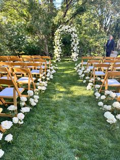 the aisle is lined with white flowers and wooden pews for an outdoor wedding ceremony