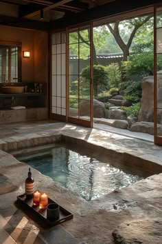 an indoor hot tub with two candles on the tray next to it and some rocks in the background