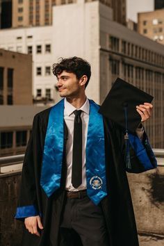 a man in a graduation gown holding his cap and gown