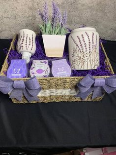 a wicker basket with soaps, candles and lavender flowers in it on a black table cloth