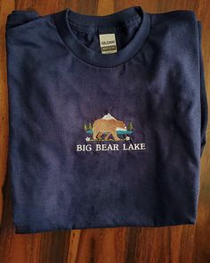 This shirt features an embroidered design of Big Bear Lake with a vintage appeal. If you have visited California's Big Bear Lake, this makes the perfect souvenir and memento to remind you of your trip.  This embroidered t-shirt is also perfect for all the camping, hiking, wildlife, and outdoor lovers! Go out, travel, and be amazed! ⭐  Product Details * Unisex Sizing * 50% cotton, 50% cotton * Embroidery will come with a backing material. This is the stabilizer and is necessary to support stitchi Big Bear Lake California, Vintage Tshirt Design, Big Bear California, California Nature, Nature Camping, Big Bear Lake, Bear Lake, Vintage Camping, Hiking Shirts