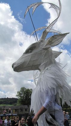 a man is dressed as a dragon with feathers on it's head and tail