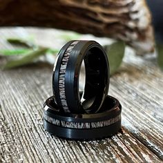 two black wedding rings sitting on top of each other