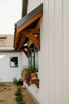 a white building with a wooden window and planter on the outside wall next to it