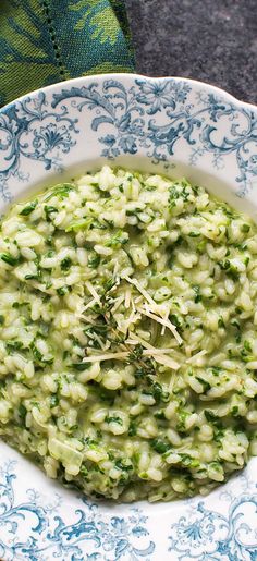 spinach risotto in a white and blue bowl on top of a table