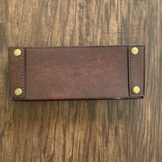 a brown leather wallet sitting on top of a wooden table