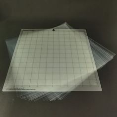 four clear plastic cutting mats stacked on top of each other in front of a black background