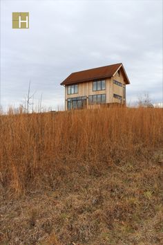 a house sitting on top of a dry grass covered hill in the middle of nowhere