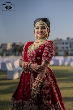 a woman in a red and gold wedding outfit posing for the camera with her hand on her hip