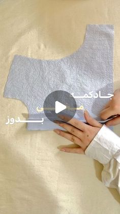 someone cutting fabric with scissors on top of a sheet of paper that has been cut into the shape of a map