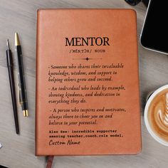 a notepad sitting on top of a table next to a cup of coffee