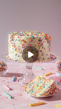 a white cake with sprinkles on it sitting on top of a table