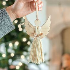 a person holding a wooden angel ornament in front of a christmas tree