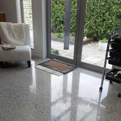 a white chair sitting in front of a sliding glass door on top of a tiled floor