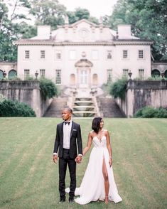 a man and woman holding hands in front of a large white house with stairs leading up to it