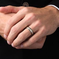 a close up of a person wearing a suit and holding his hand on the other hand