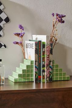 two books are stacked on top of each other in front of a vase with purple flowers