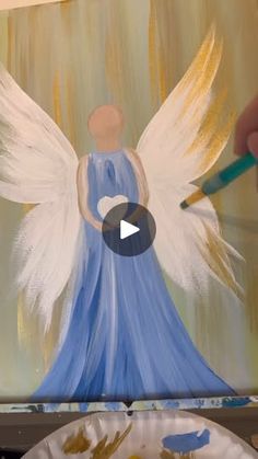 someone is painting an angel on a canvas with a paintbrush and paper plate next to it