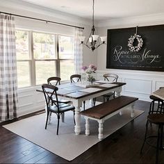 a dining room table and bench in front of a chalkboard