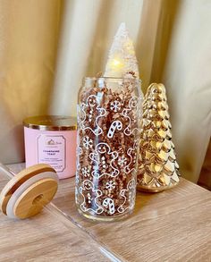 a glass jar filled with brown sugar next to two small wooden candles on a table