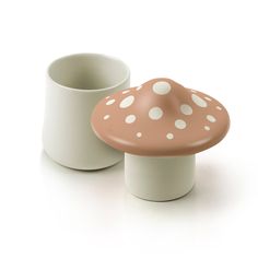 two white and brown mushrooms sitting next to each other in front of a coffee cup