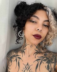 a woman with tattoos and piercings on her chest