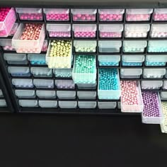 many different colored beads are arranged in bins on the shelf next to each other