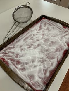 a baking sheet with white powder on it next to a strainer and grater