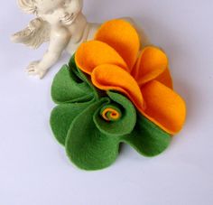 an orange and green flower sitting on top of a white table next to a figurine