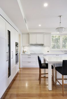 a kitchen with white cabinets and black chairs